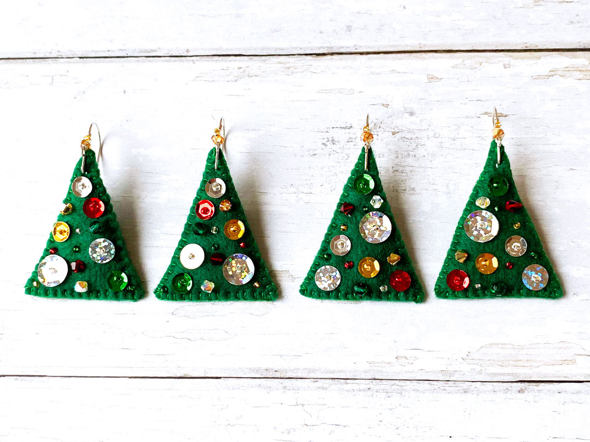 Two pairs of felt Christmas tree earrings lined up.